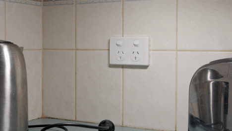 Man-turns-off-power-outlet-and-unplugs-the-kettle-and-toaster-form-the-wall-socket