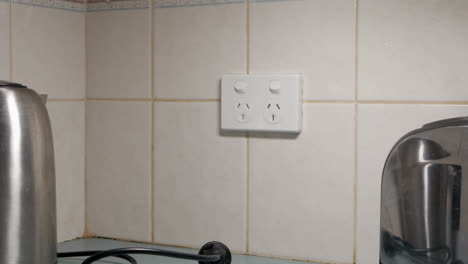 man turns off power outlet and unplugs the kettle and toaster form the wall socket