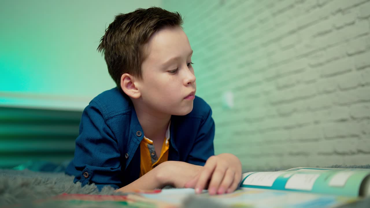 Little boy lying on bed reading book at home. Home education.