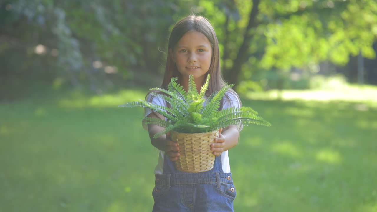 Smiling Girl Presenting a Potted Fern