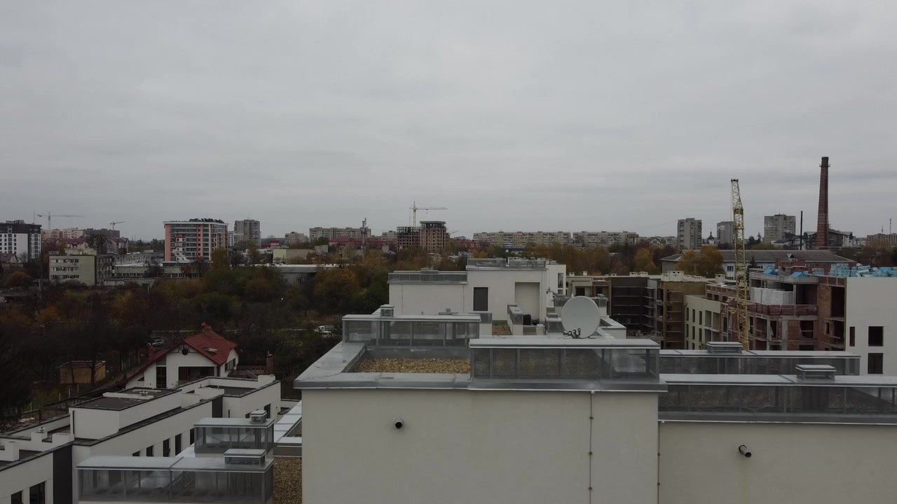 Vue aérienne d'un drone survolant des bâtiments résidentiels, avec des prises de vue de toitures et de l'architecture.