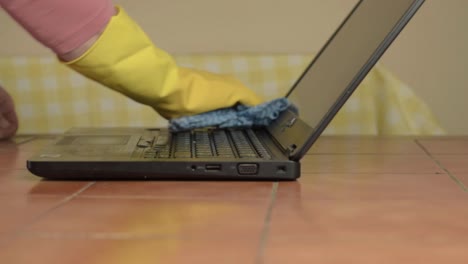 hands in rubber gloves cleaning laptop with cloth medium shot