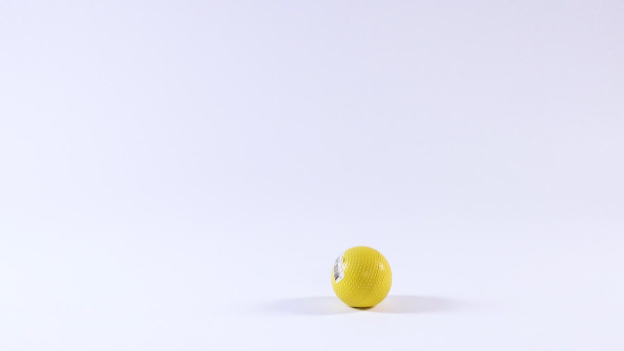A yellow ball bounces on a white surface