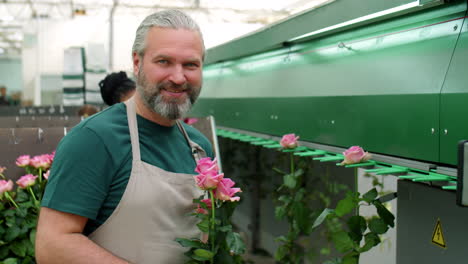 retrato de un trabajador de mediana edad con rosas en una fábrica de flores