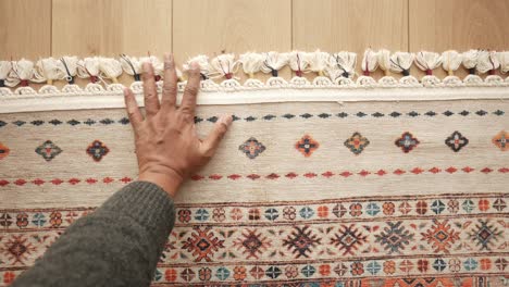 hand on a decorative carpet with ethnic design