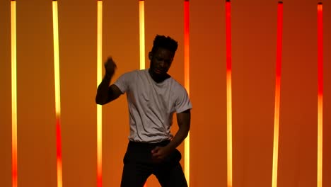 energetic young man dancing in neon lit studio