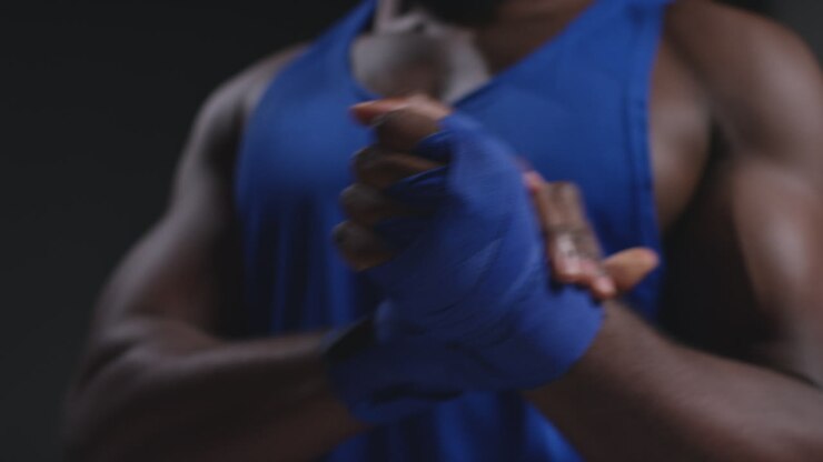 Primo piano in tempo reale di un pugile maschio con le mani fasciate con bende protettive prima di un incontro di boxe o di una sessione di allenamento