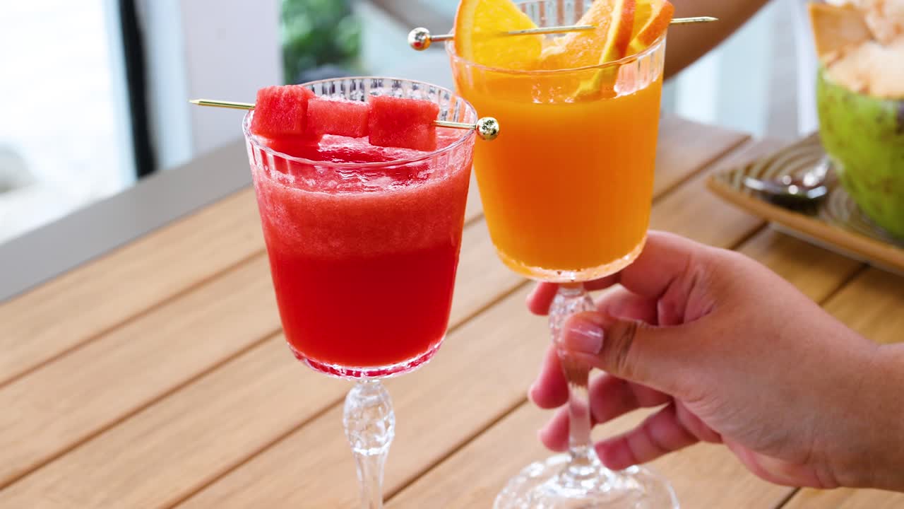 dos personas brindando con jugos de frutas de colores