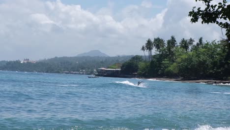 Asian-Surfer-Rides-On-Wave,-Balancing-On-Surfboard-In-The-Sea