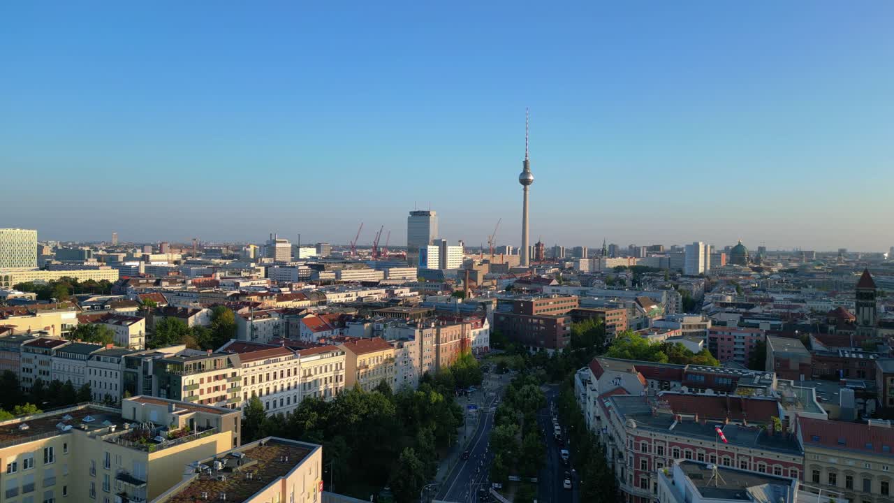 Berlin tv tower rising above rooftops and a construction site at senefelderplatz during sunset. Unique aerial view flight