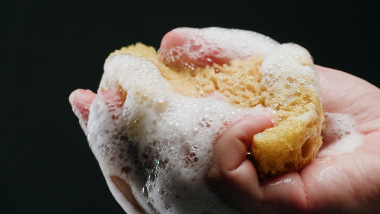Hand holding a sponge in soapy water