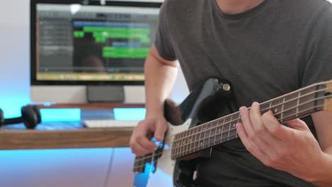 a medium shot of a man playing guitar solos, chords and rhythm with bass in a studio focussing on the hands