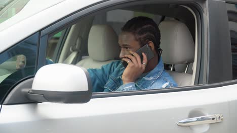 hombre afroamericano haciendo una llamada telefónica en un coche de lujo