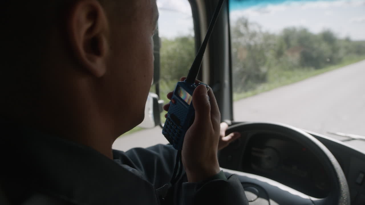 Man holding walkie talkie while driving