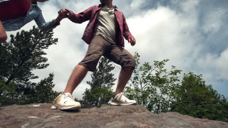 Man-helping-his-girlfriend-walk-up-a-rock