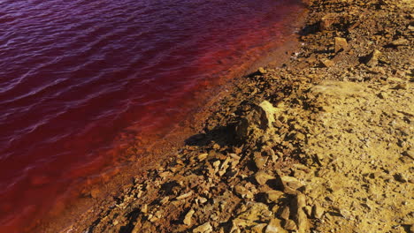 wheal maid - calm waves of hazardous coloured waters of lagoon due to mining in cornwall, england