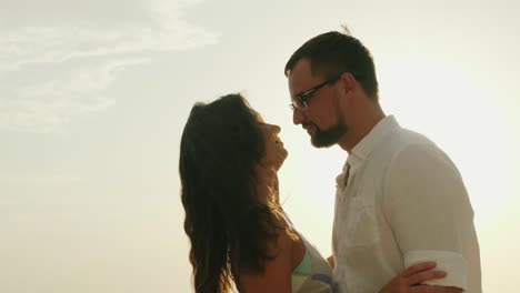 joven pareja de vacaciones junto al mar besándose en el fondo del cielo y el sol video hd