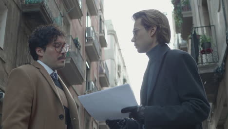 Businessmen-looking-at-documents-on-street.-Partners-discussing-papers-outdoors