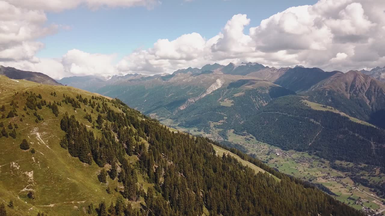 Dronový záběr letící nad horou s výhledem na údolí v dálce ve Švýcarsku ve 4K