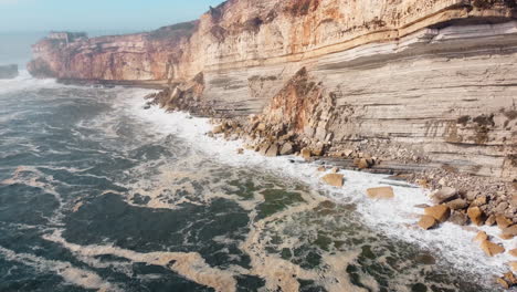 aerial of the tumultuous waters along the cliff coast of the renowned nazare in central portugal