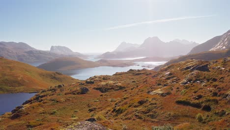 Aerial-view-of-a-beautiful-hiker-and-her-golden-retriever-dog,-running-to-admire-the-view,-Ryten-Kvalvika-Beach-hike,-Lofoten-Islands,-Norway