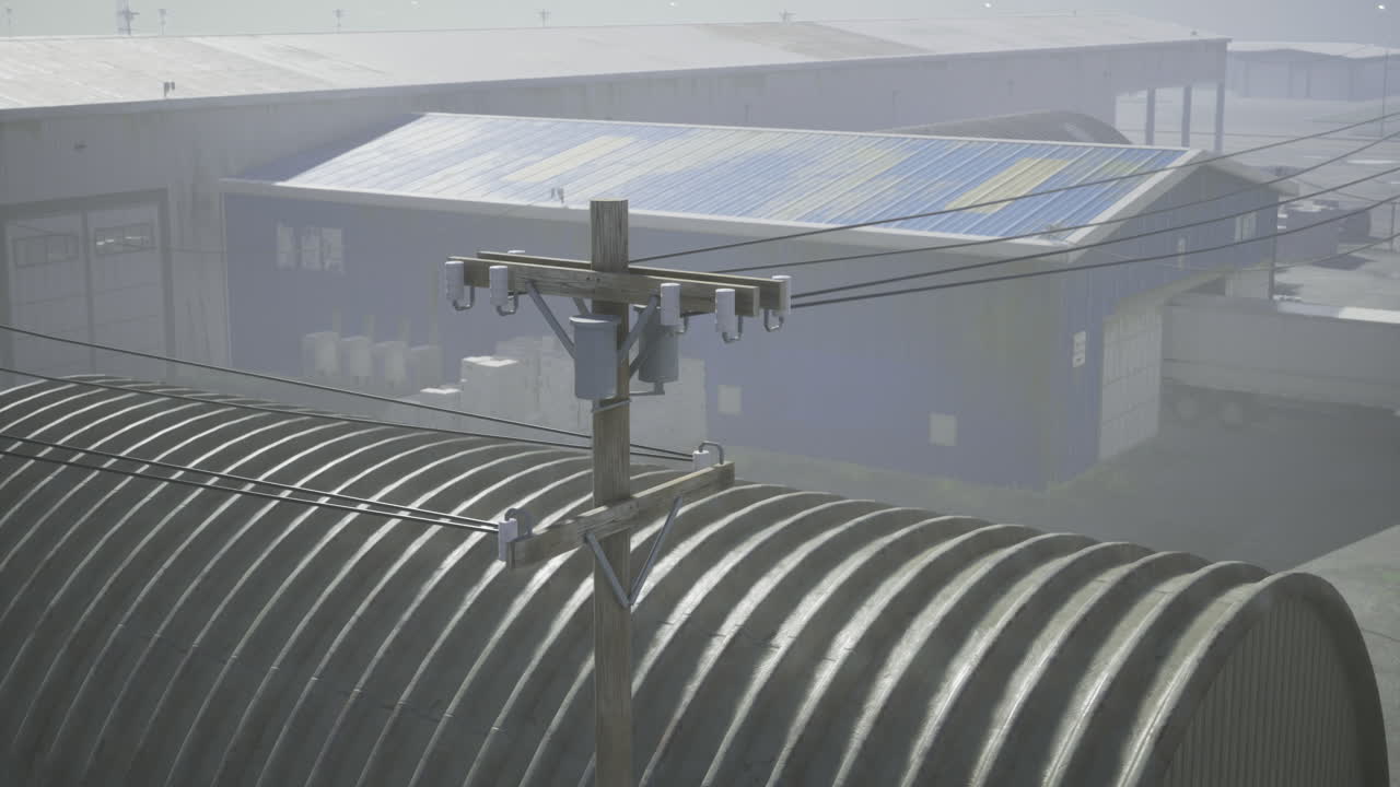 Detailed view of utility pole with solar panels and warehouses in foggy weather
