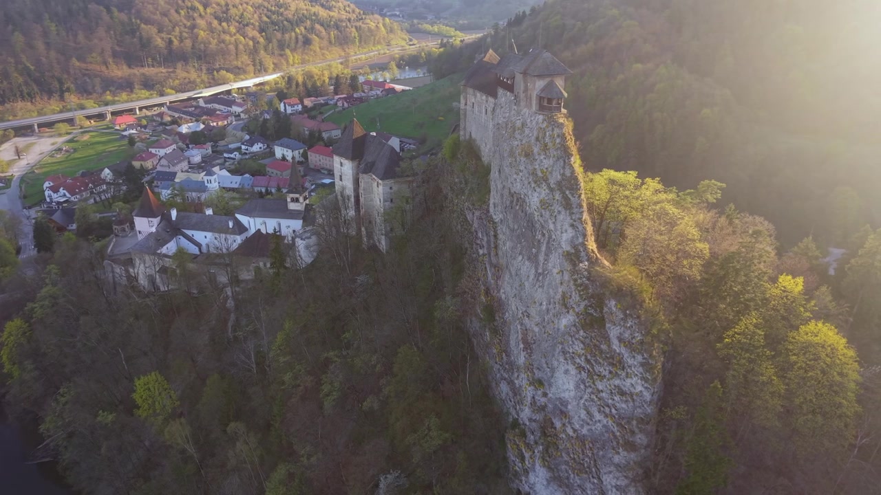 Slovakya'daki Orta Çağ Orava Kalesi üzerinde, arka planda bir nehirle manzaralı bir altın saat gün batımı sırasında uçan hava drone'u