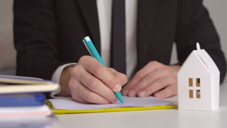 cierre del agente inmobiliario trabajando firma documento de acuerdo contrato para el seguro de préstamo de vivienda aprobando compras para el cliente con modelo de casa de papel.