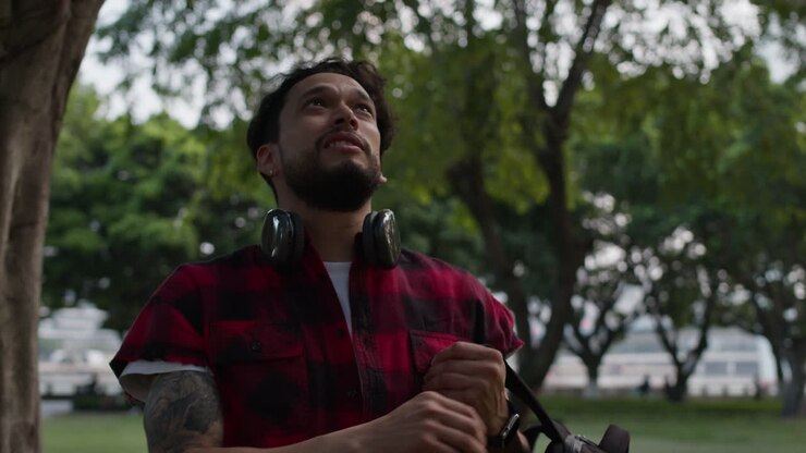 um homem a ouvir música num parque.