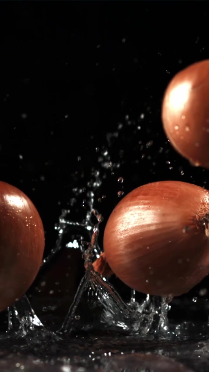 Onions Falling into Water in Slow Motion on Black Background