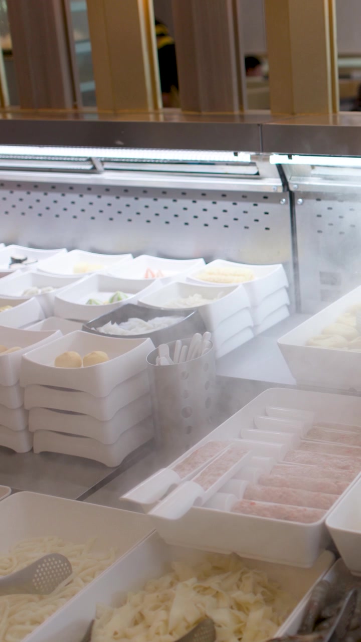 A slow panning shot across a refrigerated buffet counter with fresh vegetables and cooling mist