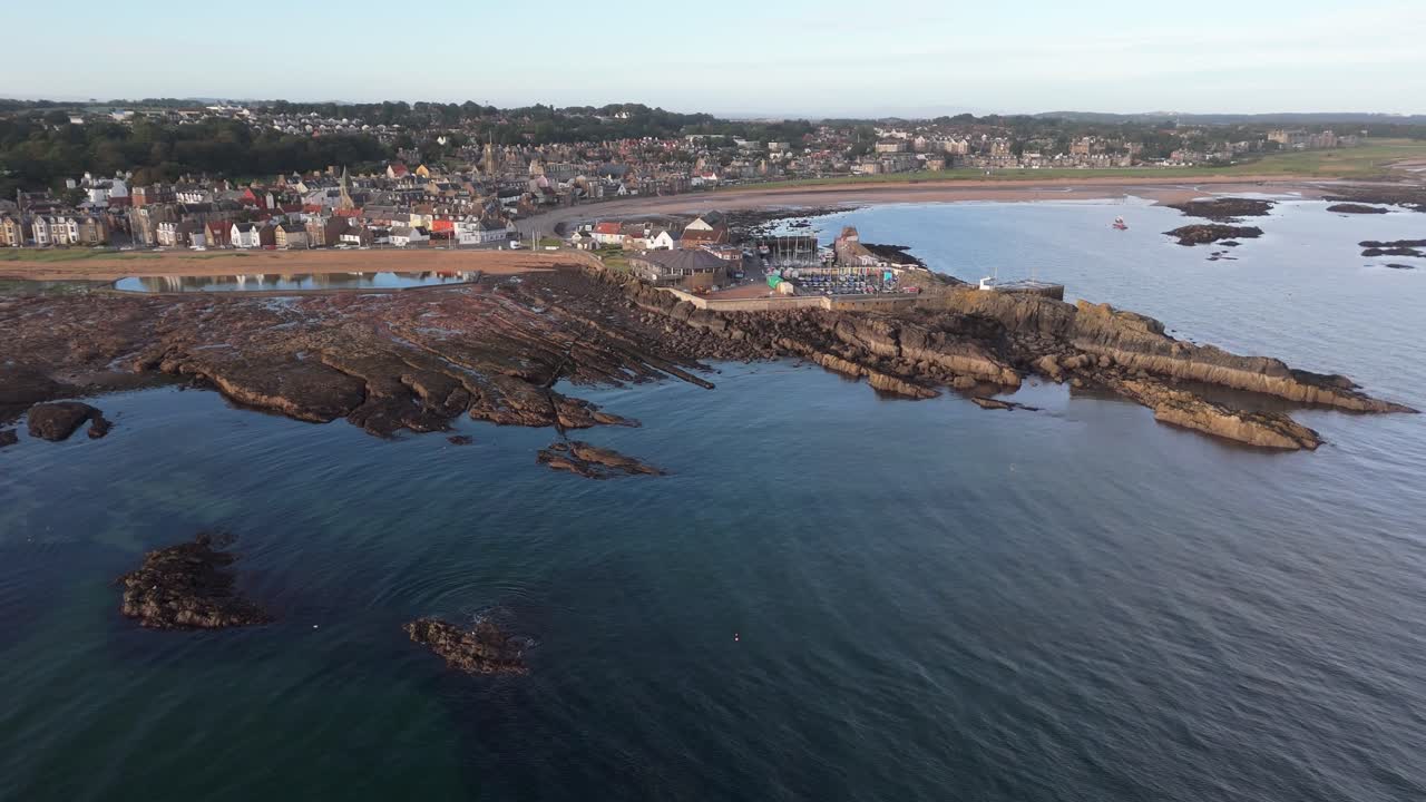 Aerial footage of North Berwick, Scotland in golden morning sunlight. stunning views of the town’s historic harbour, sandy beaches, and rugged coastline along the North Sea