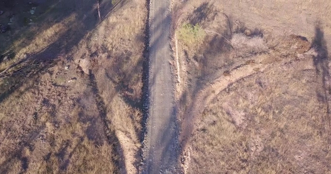 Volo aereo su una strada in Australia con prateria circostante, prospettiva a volo d'uccello che avanza