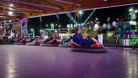 excited friends driving bumper car in amusement luna park. happy girls enjoying