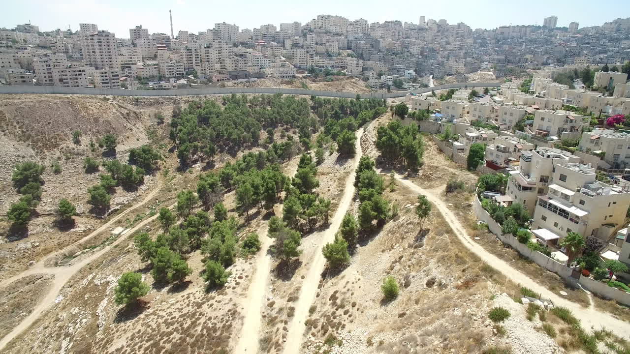 Aerial view of a city on a dry hillside with a separating wall