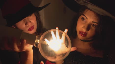two witches examining a light bulb