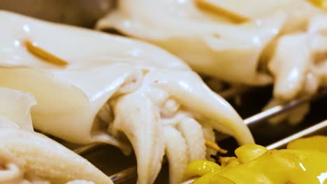detailed view of squid and yellow peppers being grilled, showcasing texture and color.