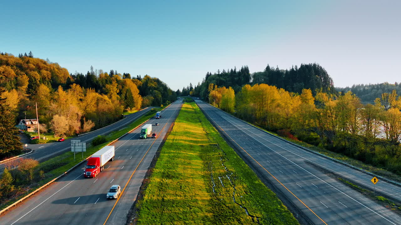 Two-ways highways in the sunny countryside. Automobiles and lorries ride by the rural area at sunset. Top view.