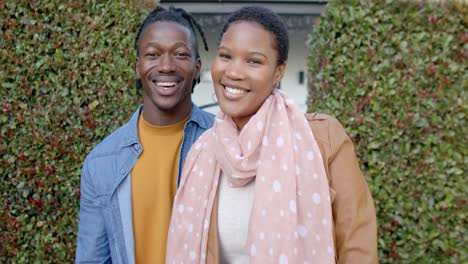 portrait of happy african american couple standing outside house, slow motion