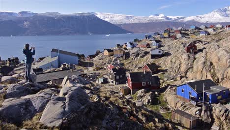 uummannaq 그린란드의 qilakitsoq에서 다채로운 주택과 karajak fjord를 내려다보는 등산객의 패닝 동작