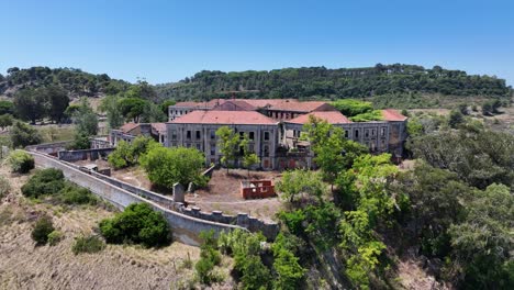 Drone-footage-of-a-deserted-spookey-mansion-on-a-hill-by-Porto-Brandao,-south-of-Lisbon