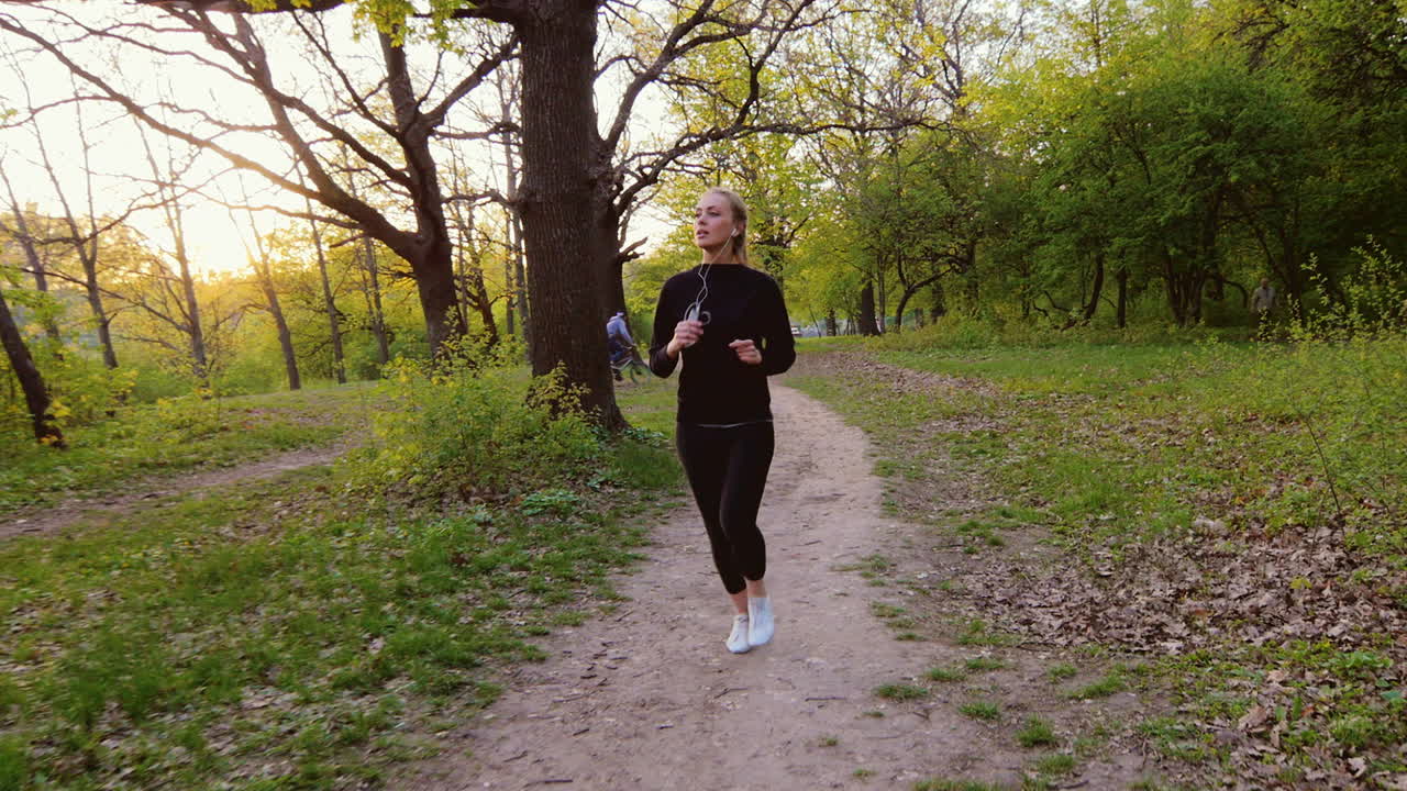 봄 숲에서 조깅하는 여자 숲에서 실행 태양이 뒤에서 빛나고있다