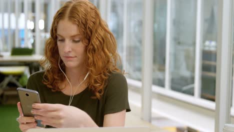 Businesswoman-listening-music-on-mobile-phone-at-desk-4k