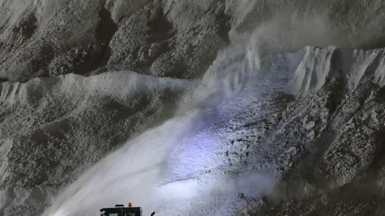 Large Snow Pile With Snow Blower Adding To It At Night In Montreal