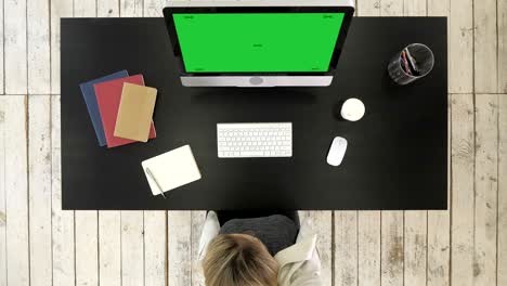 woman working at computer in office tired drinking coffee. green screen mock-up display