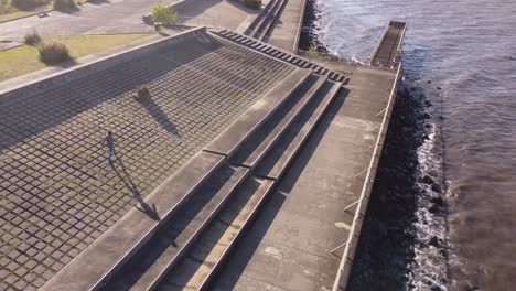 Joven-Aislado-Caminando-Por-El-Pavimento-De-Hormigón-Frente-Al-Mar-Con-Formas-Geométricas,-Buenos-Aires-En-Argentina