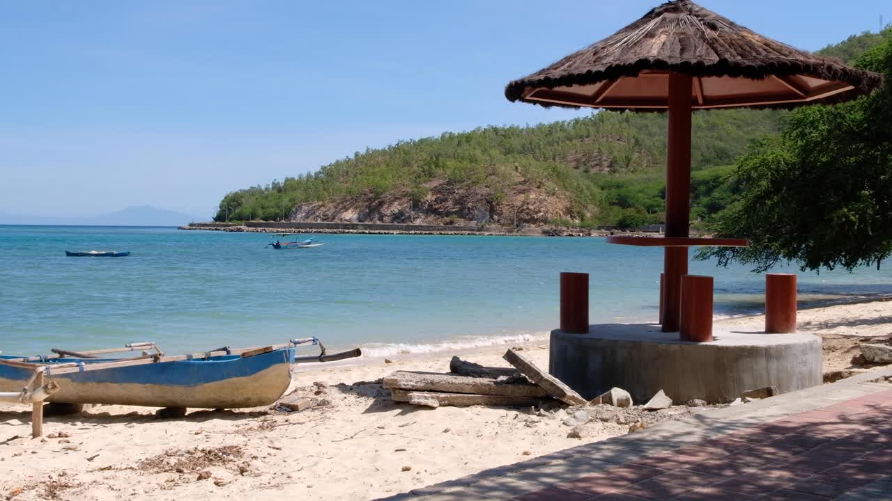 Scenic landscape view of white sandy beach, moored fishing boat and turquoise ocean in Dili, Timor-Leste, Southeast Asia