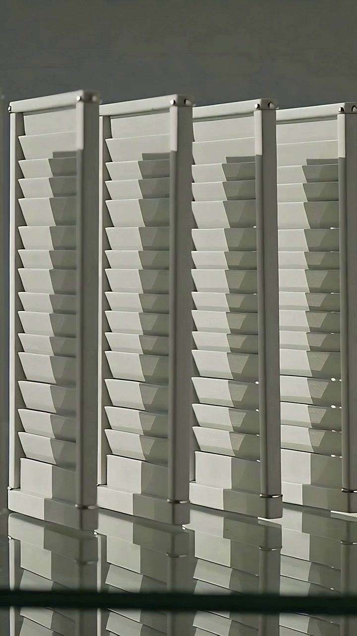 Vertical video: Panning camera right and up, showing cream slatted shutters with reflections, posts