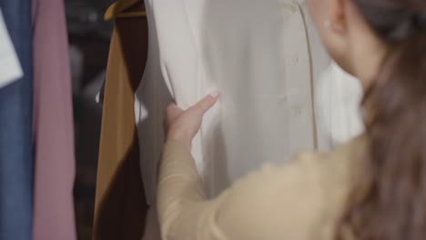 직장 면접 2를 위해 옷 레일에서 비즈니스 정장을 선택하는 집에서 여자의 닫습니다