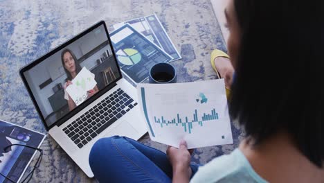 African-american-woman-holding-a-document-having-a-video-call-on-laptop-at-home